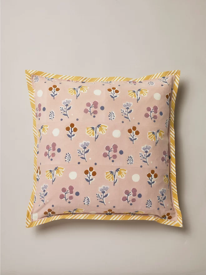 Small multi coloured floral design block printed dusty pink cushion with white and yellow stripe border trim  