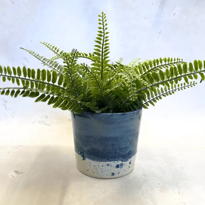 Shoreline Large Pot, a colourful pot placed on a stone surface. It is accompanied by a plant. 