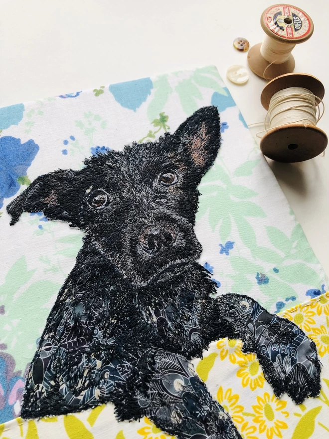 close up of an embroidered pet portrait of a black dog hanging over a bath edge