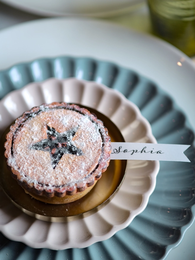 A festive handpainted wooden mince pie place setting with handwriten note to welcome your guests at the Christmas table