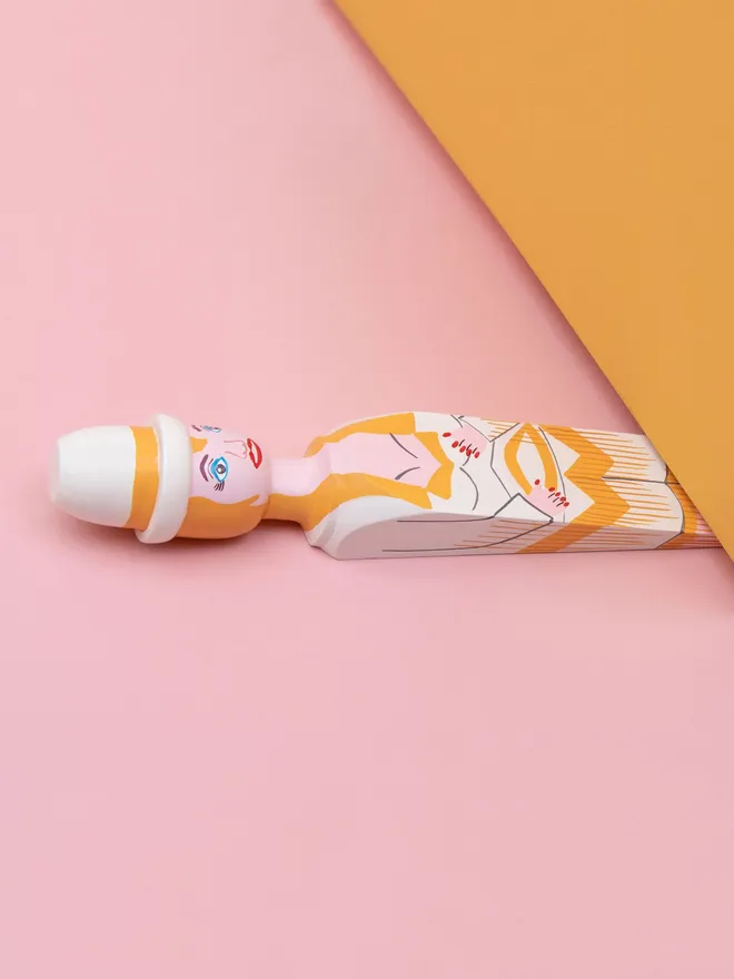 Wooden Door Stopper (Doll Gold Outfit), a colourful wooden door stop sitting under a door.