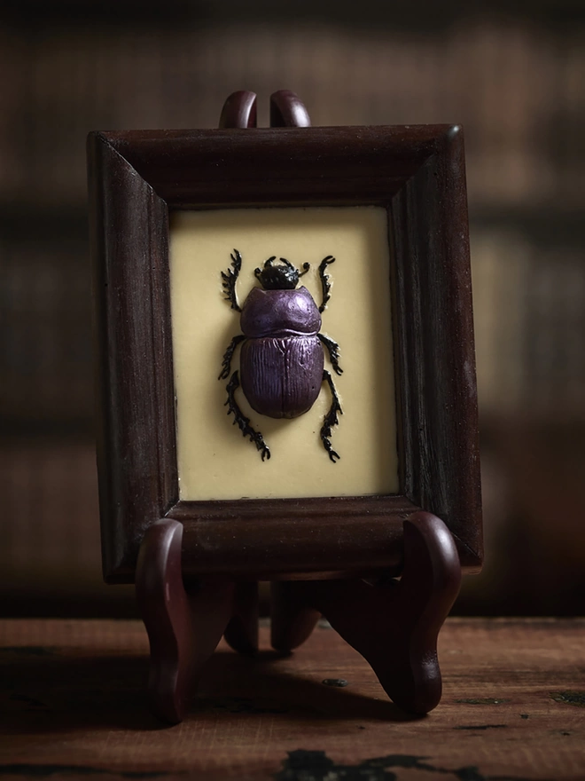 Realistic edible chocolate dung beetle in chocolate frame on antique background
