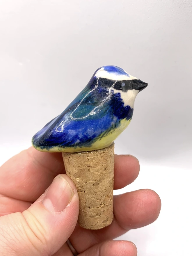 Blue Tit Ceramic Bird Bottle Stop, a bird themed bottle stop sitting on a wine bottle outside