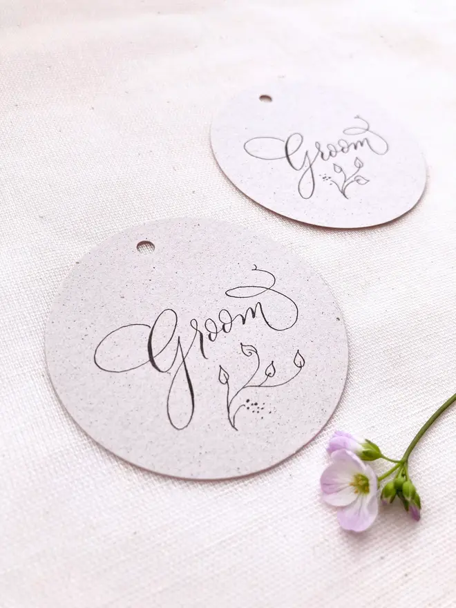 circular calligraphy wedding place cards. white circular place card with black calligraphy.