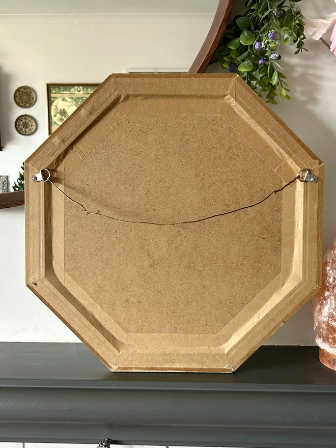 Medium sized octagonal wall mirror with a hand painted decorated frame with gold stars and blue star burst repeating pattern around the frame