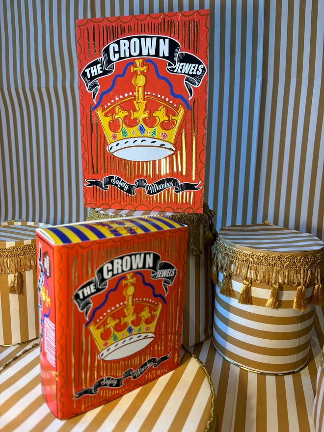 The Crown Jewels Matchbox, a red matchbox with a crown design sitting on a decorated surface accompanied by other accessories. 