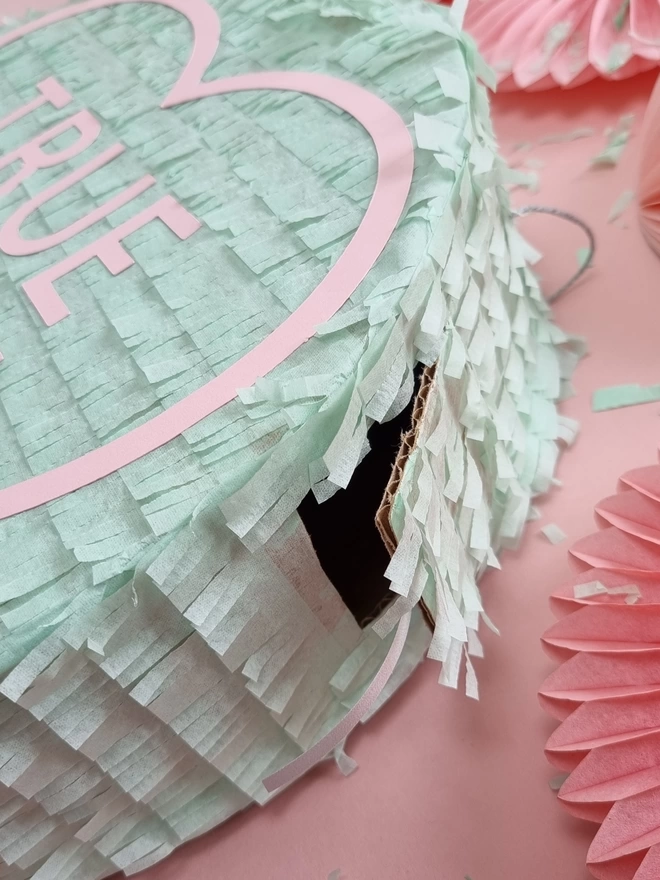 close up of the pinata opening. a small door cut into the side of a mint green pinata