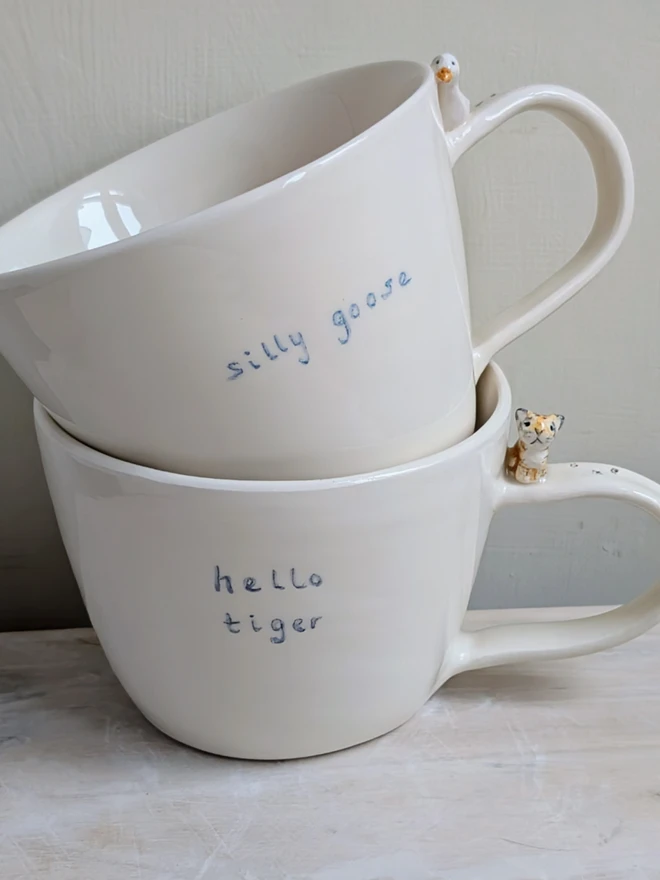 Handmade hello tiger cup in white earthenware ceramic with a tiny stripy cat and hand painted words silly goose