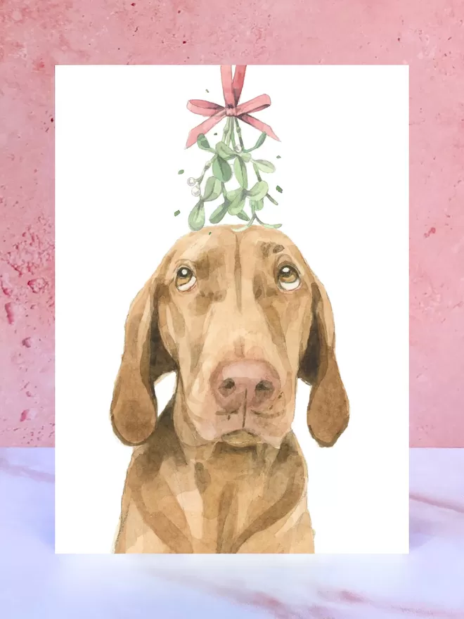 A Christmas card featuring a hand painted design of a Vizsla, stood upright on a marble surface.