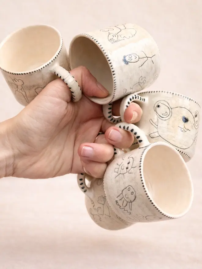 A selection of ceramic mugs personalised with children's drawings on them
