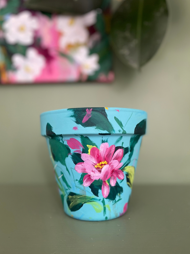 Hand painted floral pot in pale teal background bright pink zinnia flowers 