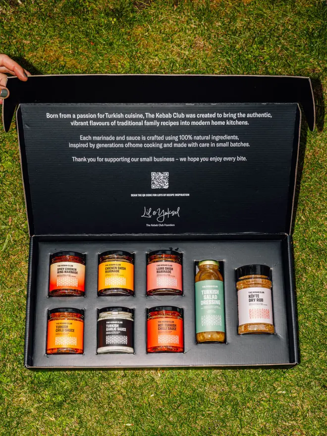 Open gift box displaying all sauces included in the box and on a grass background
