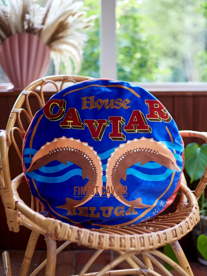 Caviar Tin Cushion, a colourful cushion with a caviar design on it. It sits on a chair. 