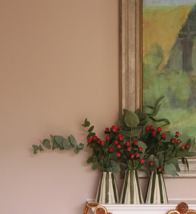 three christmas vases sitting on a christmas decorated mantle piece