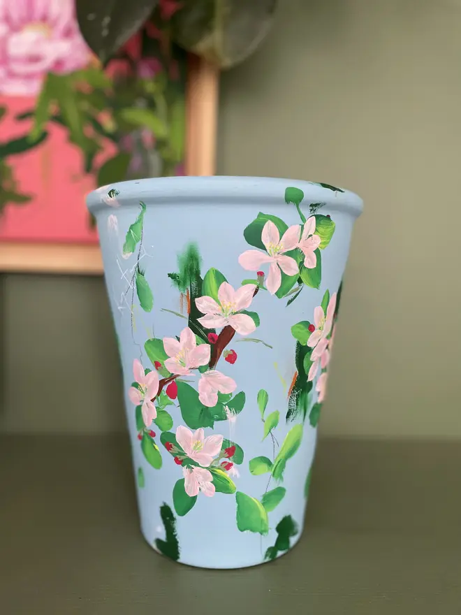 hand painted floral terracotta interior plant pot pale blue background pink apple blossom flowers