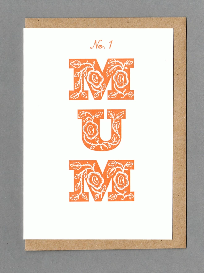 White card with orange text reading 'No. 1 Mum' with a kraft envelope behind it