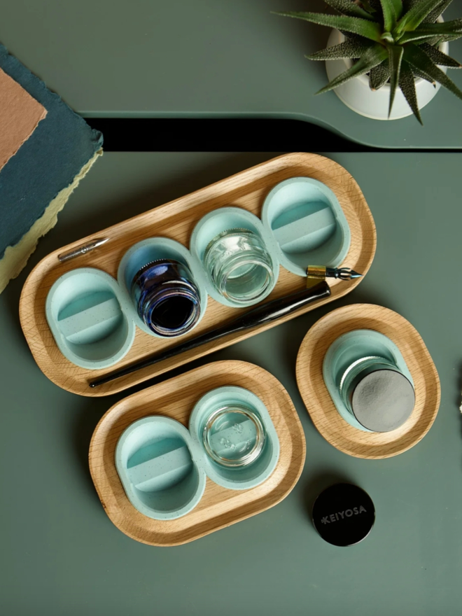 Versatilt Ink Stand. All sizes of pot shown together, with a two-pot holder, a single holder, and a four-pot holder. They are in Marble Teal.