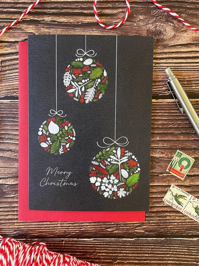 Christmas Card with 3 Bauble Design on Red Envelope - Wooden Background, Vintage Stamps, Silver Pen, and Red & White String