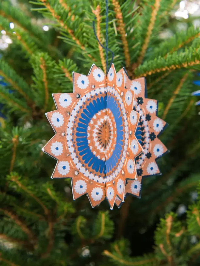 Close-up blue and orange star decoration hanging on tree