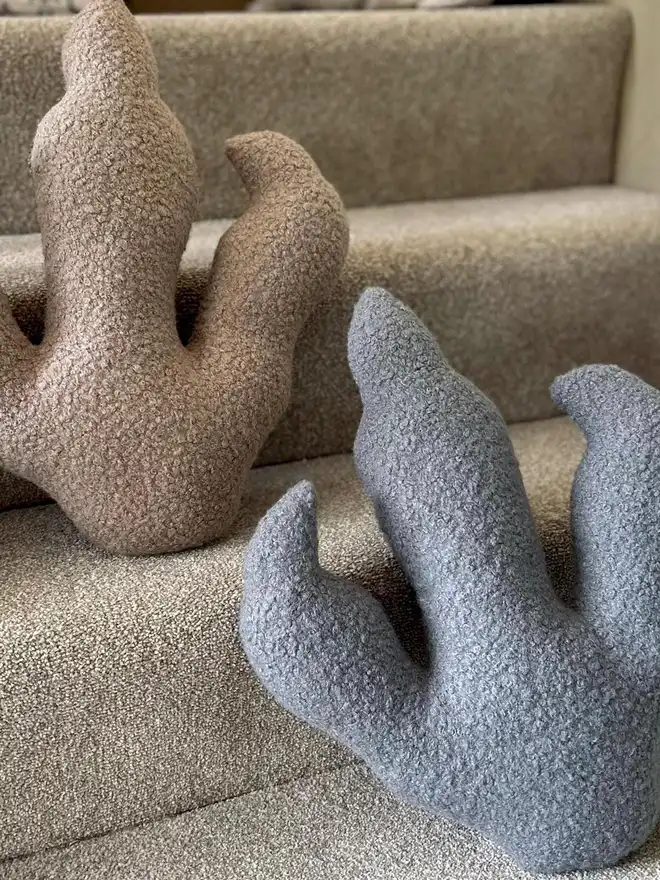 boucle dinosaur footprint cushion. brown and blue dinosaur print cushions photographed on stairs.