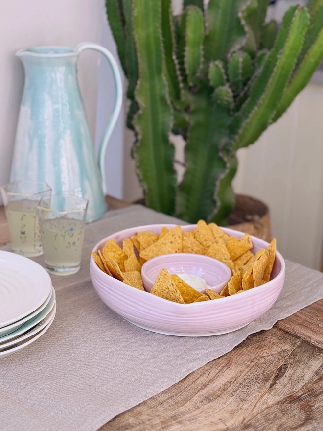 Heart shaped chip and dip bowl with tortilla chips and dip on a rustic wooden table