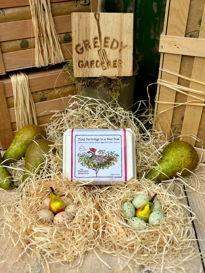 Chocolate eggs and pears nestled in wood wool bird nests surrounded by pears in front the of Greedy Gardener's gifting crate