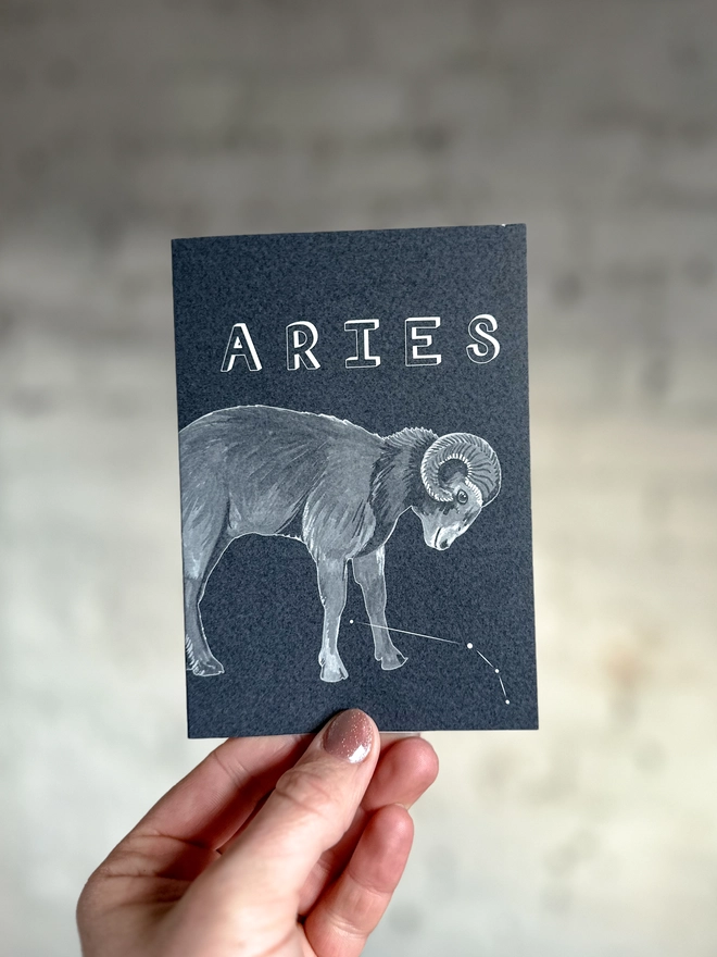 a greetings card featuring a greyscale illustration of a zodiac style ram with the text “ARIES”