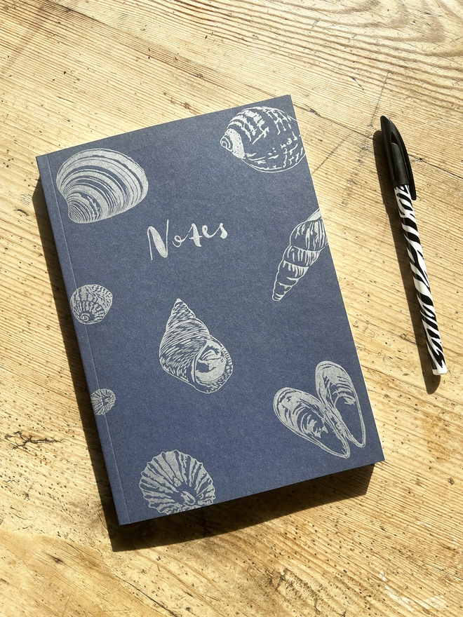 Front of the Shell notebook showing multiple shells with a pen next to it.