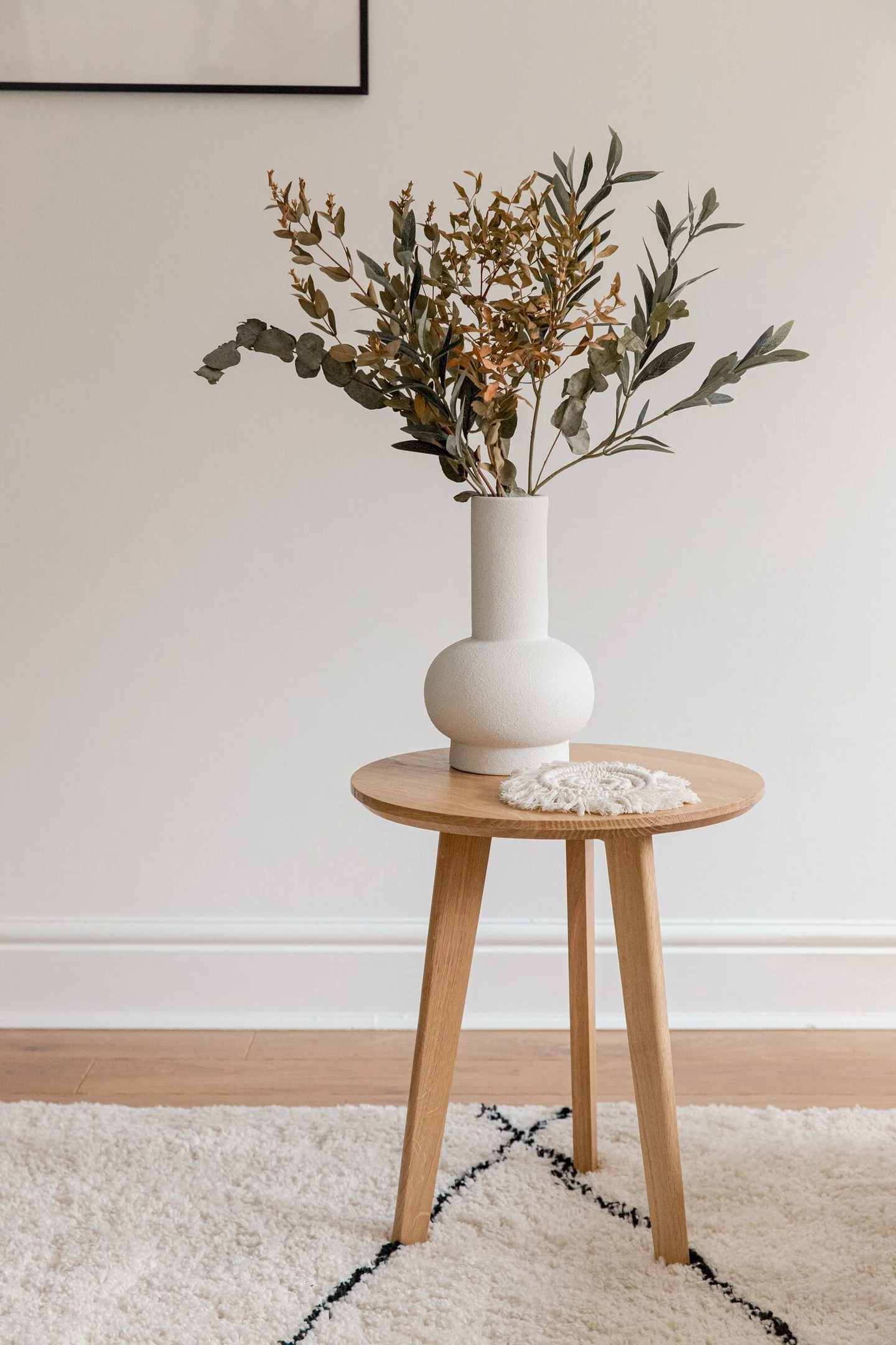 Handmade Solid Oak Side Table, a wooden side table sitting on a carpet in a living room. It is accompanied by a vase and a picture. 