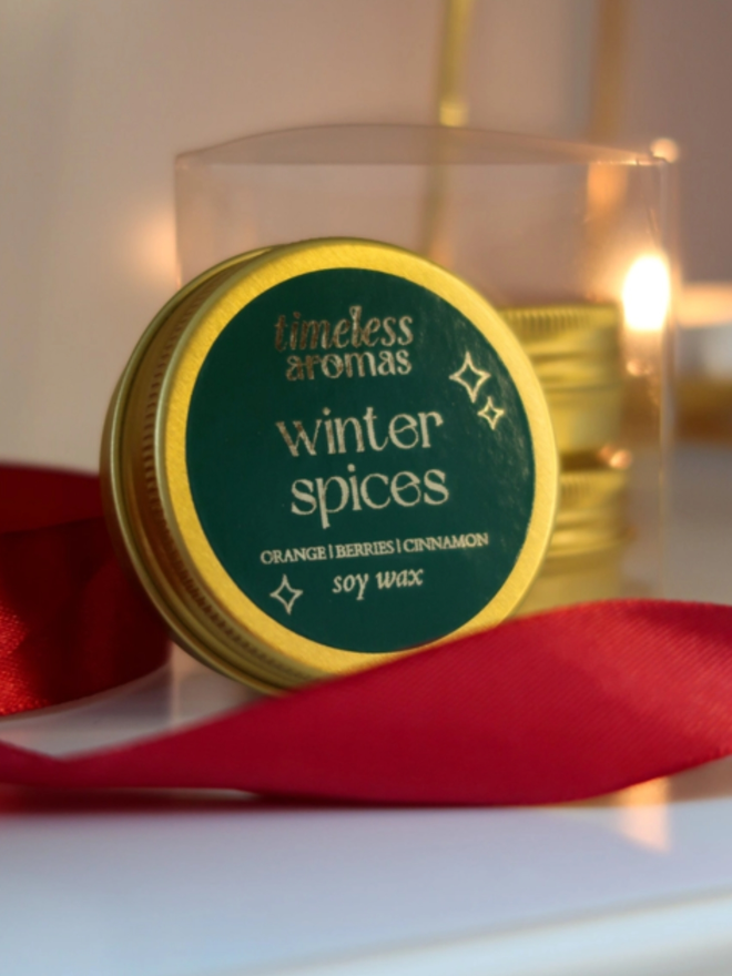 personalised calligraphy christmas crackers. a soy candle in a round gold tin.