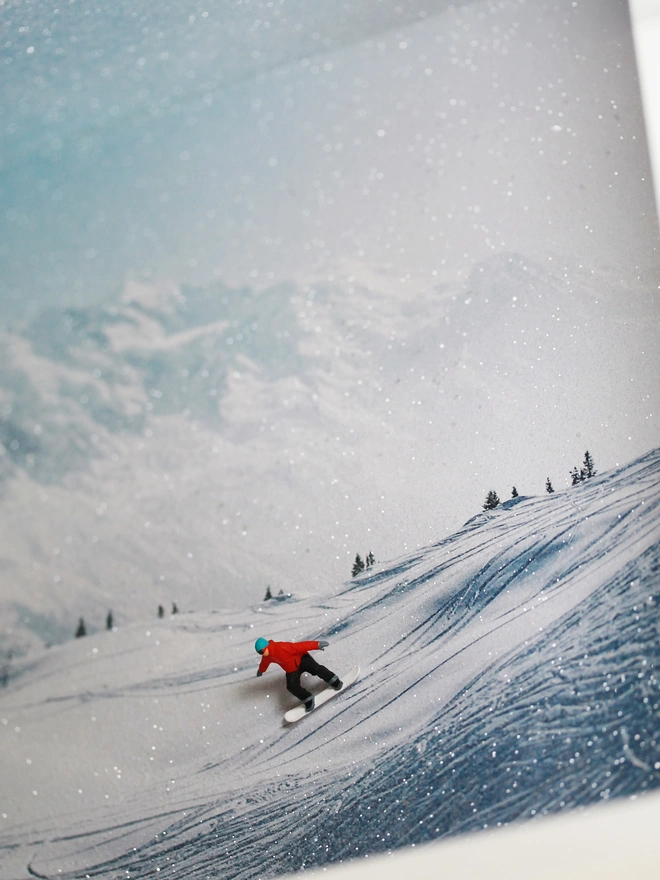 Miniature scene in an artbox showing a tiny snowboarder cruising down a snowy mountainface
