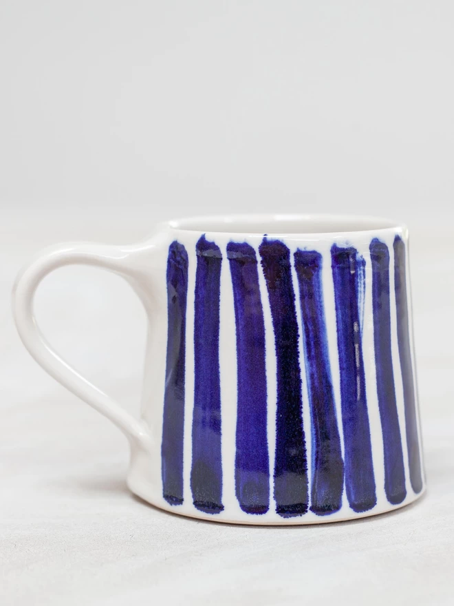 Gloss handmade mug with cobalt blue hand-painted stripes seen from the side