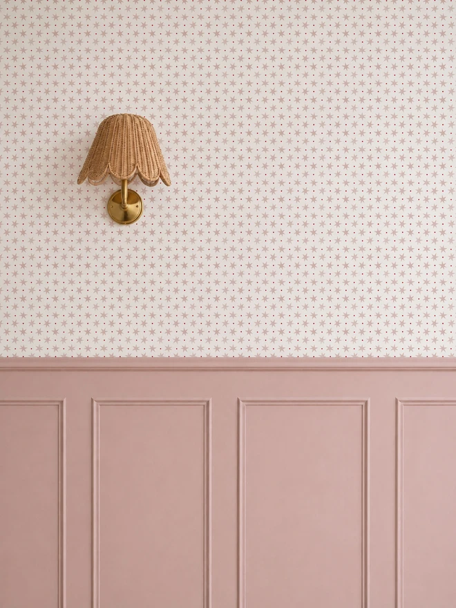 Ducks In A Row Stars & Spots Blush Wallpaper in Girls bedroom with pink wall panelling and wicker scalloped wall sconce