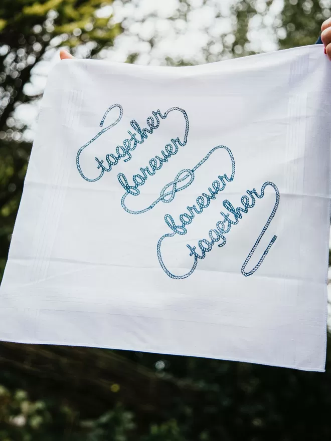 A Mr.PS Together Forever printed handkerchief held aloft in a sunny garden