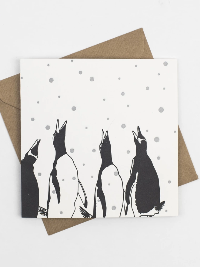 Full image of Four penguins looking up calling with silver snowdrops falling around them