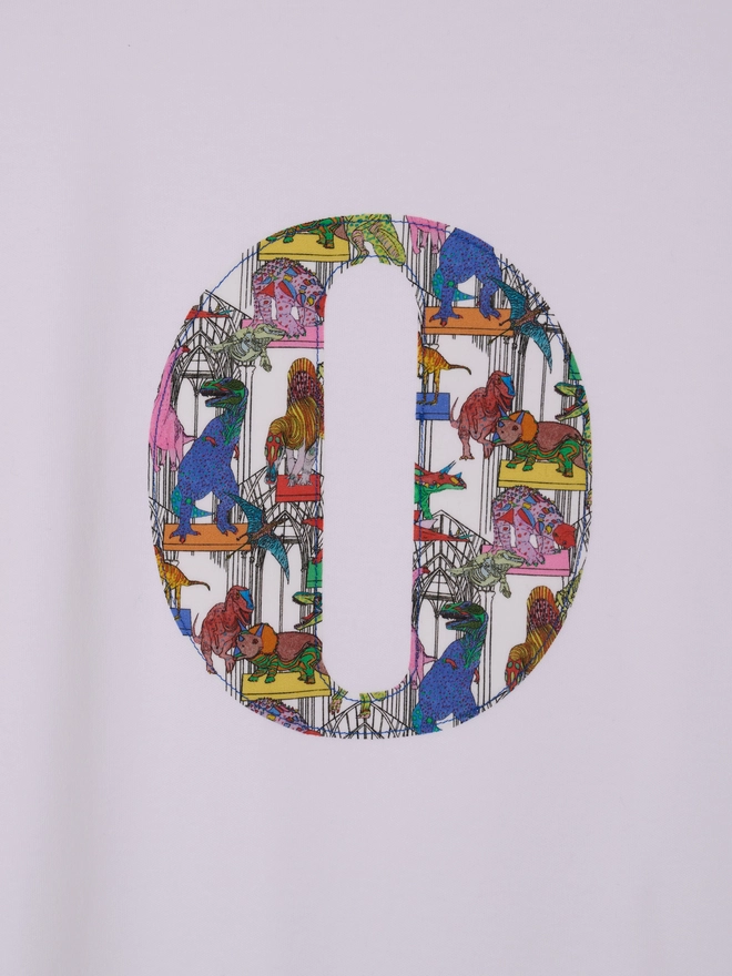  a personalised kids white t-shirt with an initial cut from liberty dinosaur print on the front, a close up of the stitching 