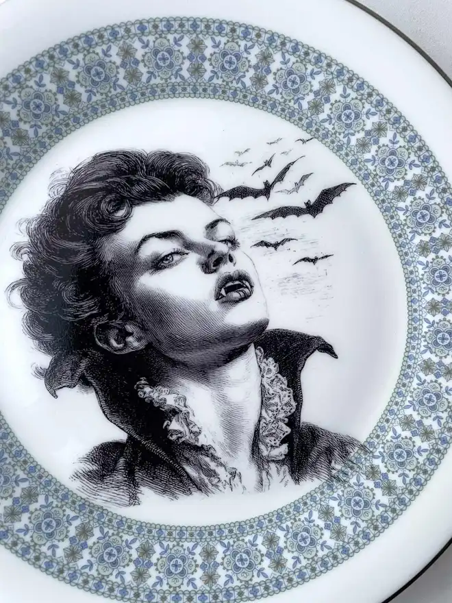 the vampire Lestat wtih bats behind him, the image is victorian in black and white and is printed directly onto an ornate vintage plate
