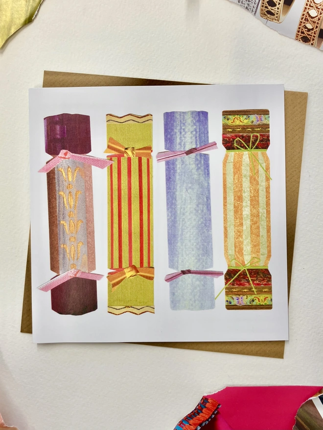 Christmas card featuring 4 colourful cracker collages on a white background with a brown envelope on a desk with collage papers