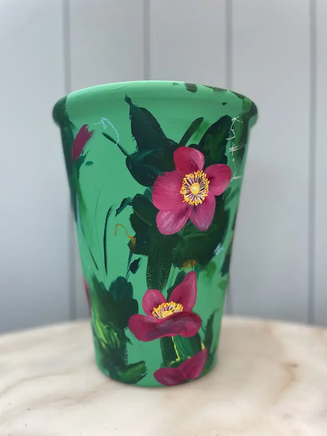 Unique hand-painted terracotta pot featuring deep pink anemone on a turquoise background