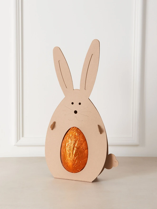 orange milk chocolate easter egg. a chocolate egg in orange foil in a cardboard rabbit