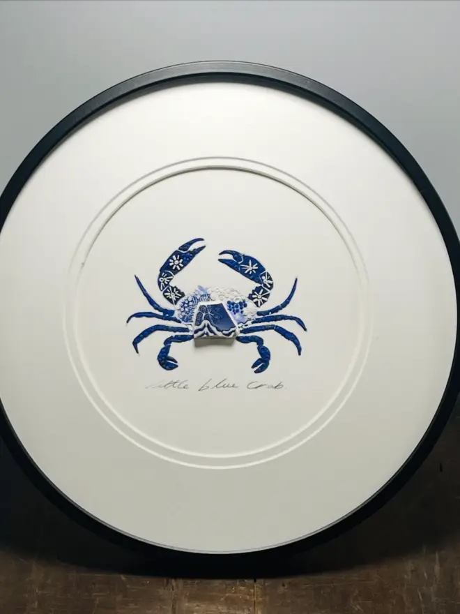 Hand-drawn, painted, mosaic clay, blue vintage Willow Tree pottery insect on white double mounted card, in a black circular frame.