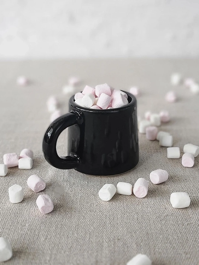 Classic Ceramic Espresso Mug, a colourful ceramic espresso mug sitting on a plain surface against a white backdrop. It is accompanied by a group of marshmallows. 