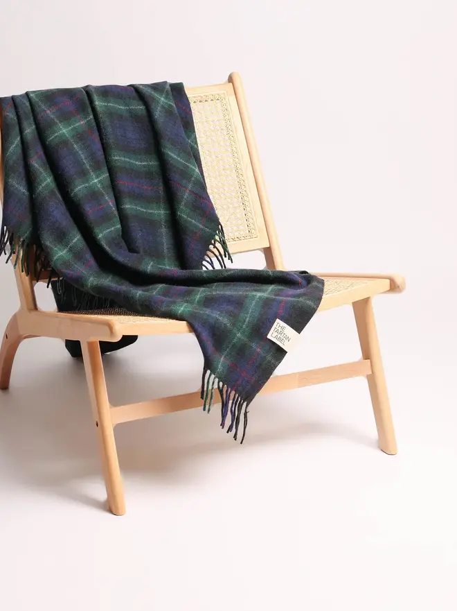 Mackenzie Wool Blanket, a wool blanket draped over a wooden chair on a plain surface against a white backdrop. 