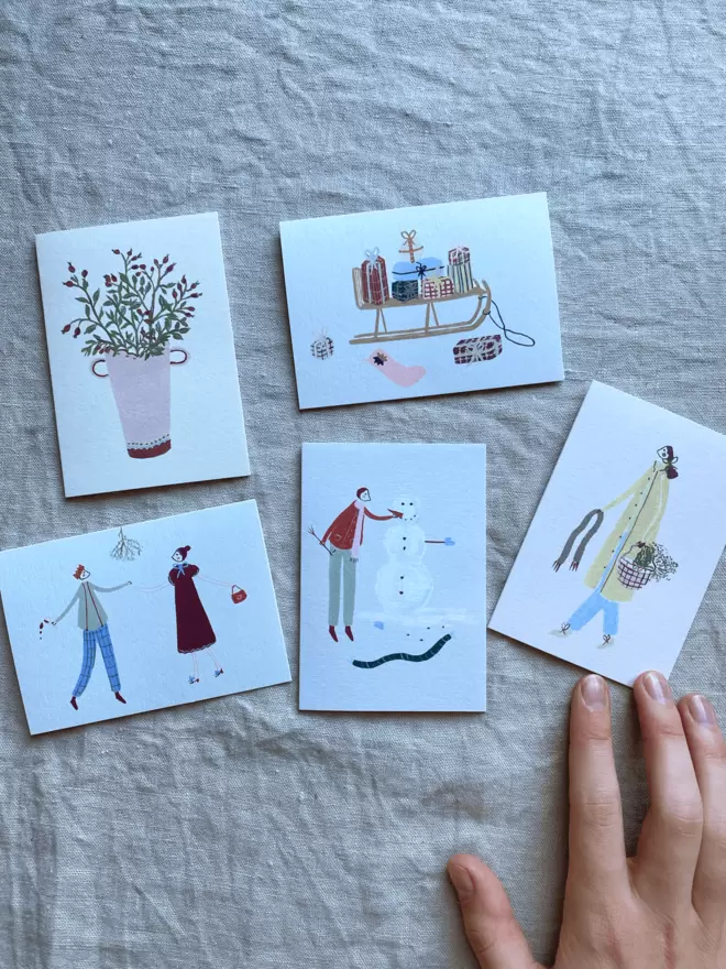 selection of mini christmas cards with people celebratings and playing in the snow on. 