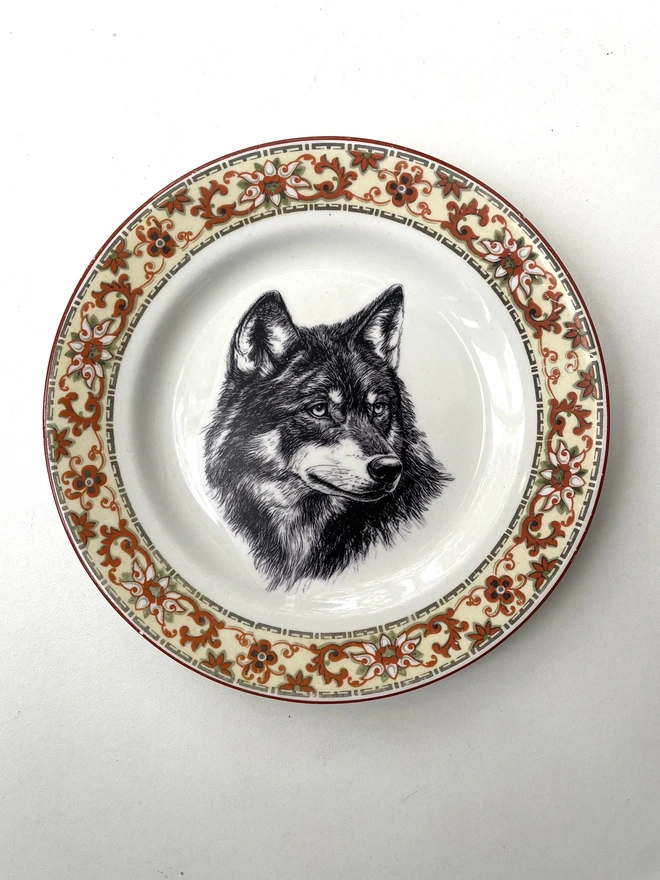 a vintage plate with an ornate border, in the centre of the plate is a vintage style black and white illustration of a beautiful wolf