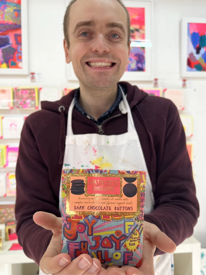Happy artist holding bright colour bag of full of joy charity dark chocolate buttons perfect gift