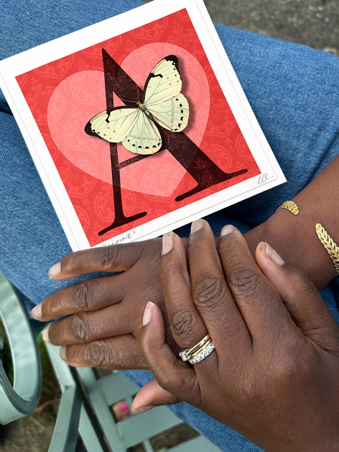 Recipient holding their personalised birthday butterflygram with a black letter A and a 3D White pop out butterfly on a red background.