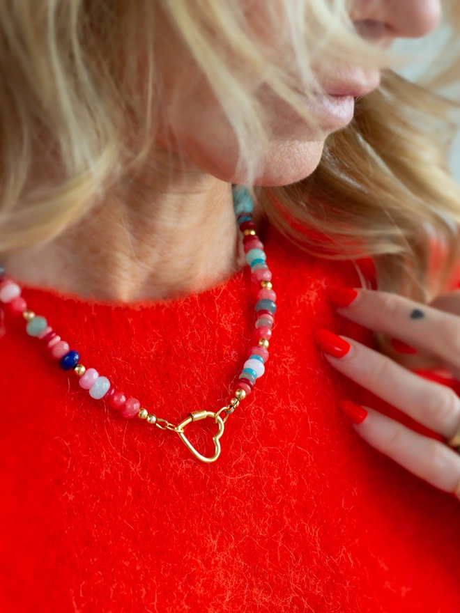 Bring sunshine to your jewellery stack with the Love Drunk Necklace. Featuring coral red jade, cooling aqua agate and gold plated beads, this colourful beaded necklace is fastened with a playful heart carabiner. A joyful statement necklace designed to lift your mood, brighten your look and add effortless summer vibes.