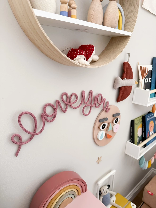 "I love you" knitted wire word art hanging up on a nail on the wall. 