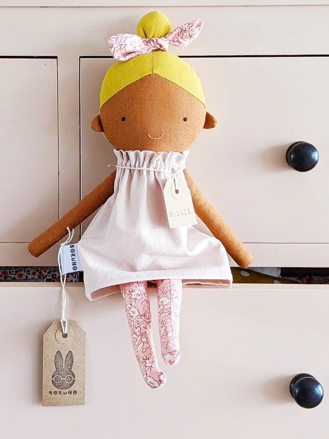 blonde doll with brown skin and pink dress
